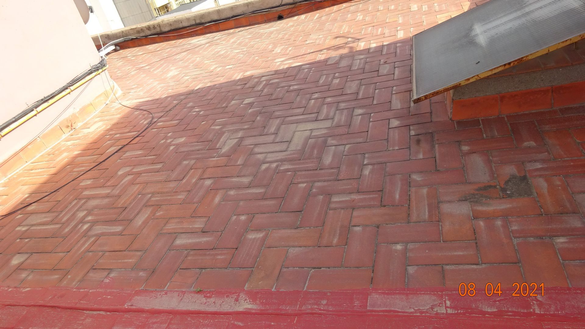 Un suelo de ladrillo rojo con diseño de espiga y un techo al fondo.