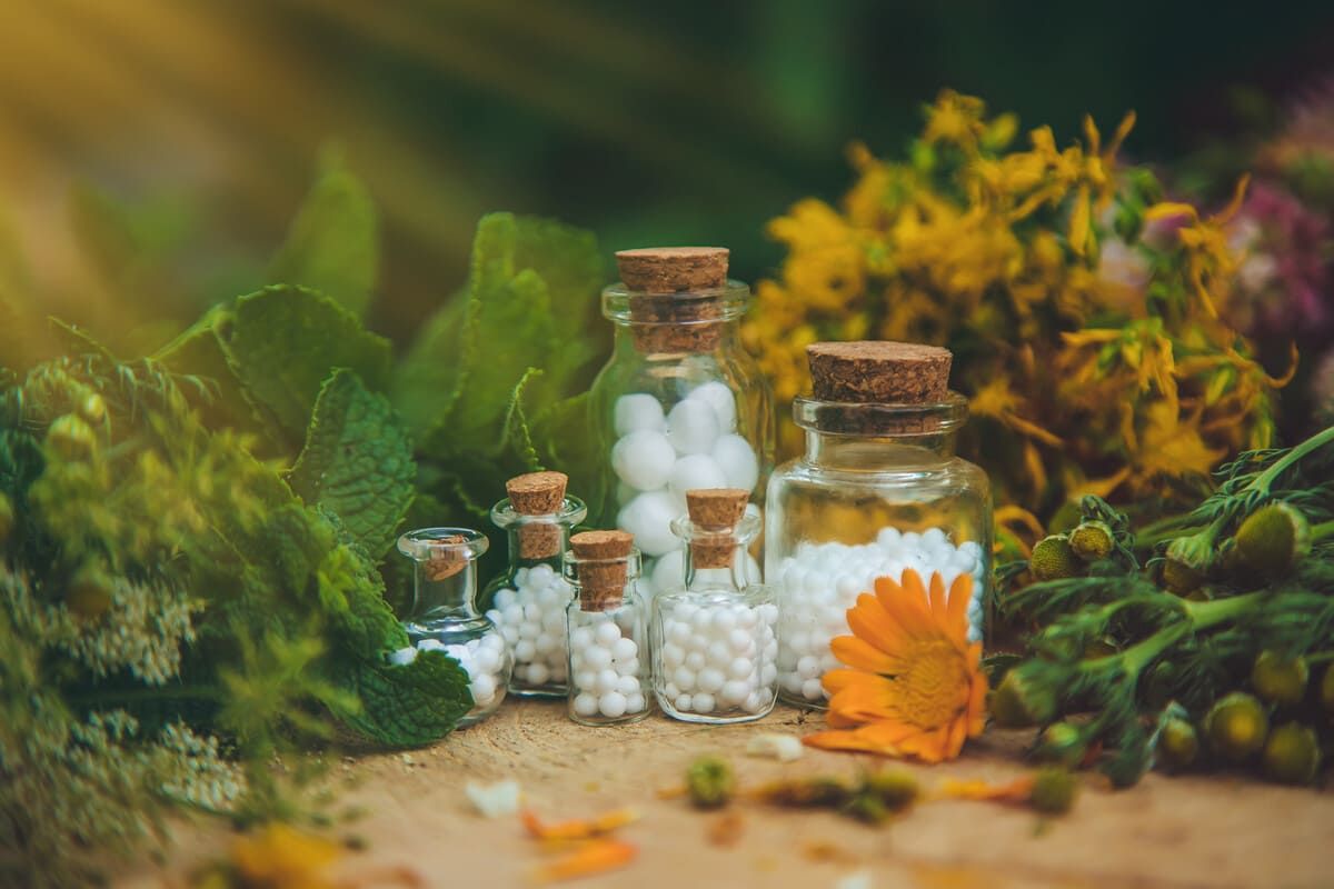 Hay muchos frascos de pastillas de homeopatía y flores sobre la mesa.
