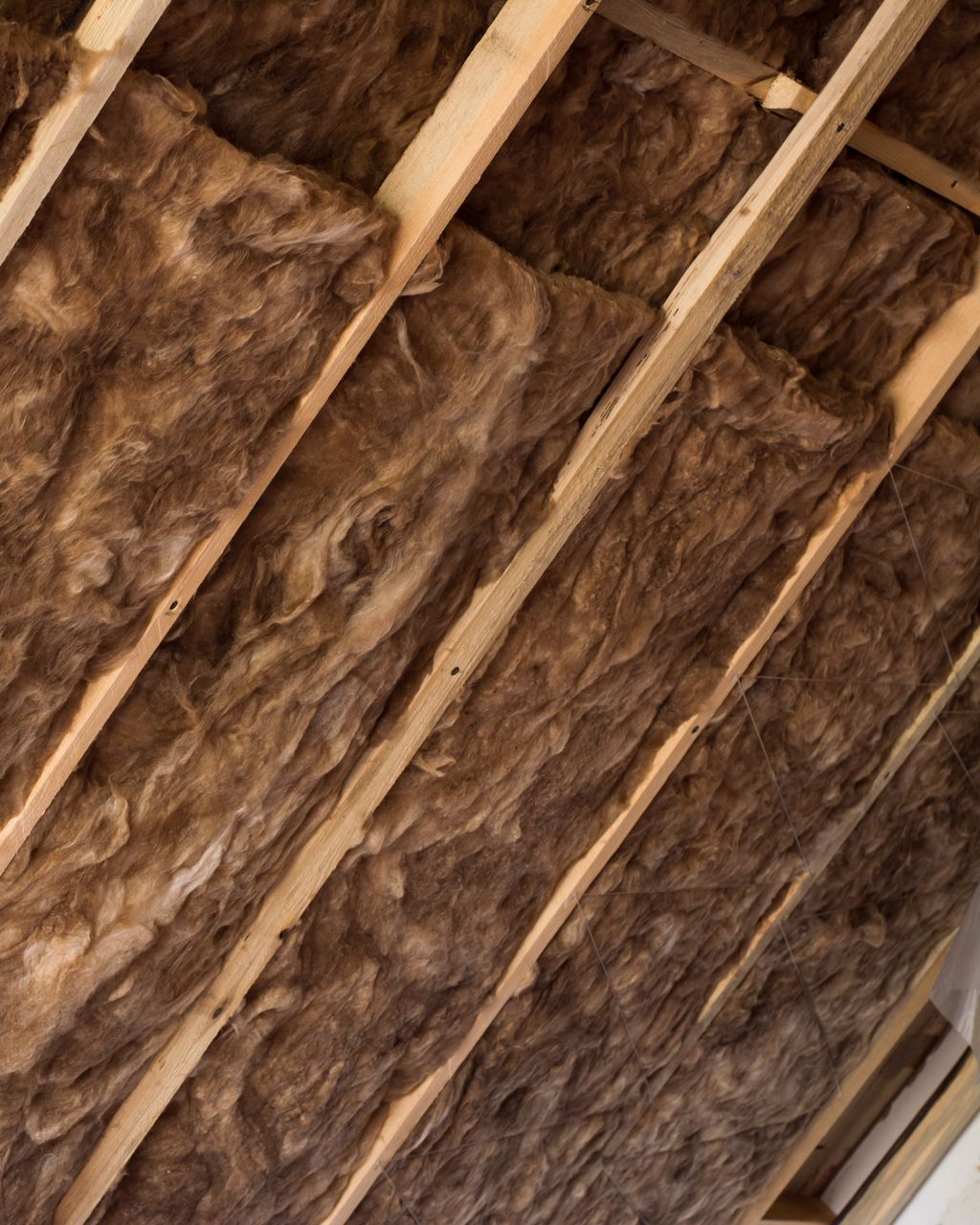 Poutres en bois avec isolation brune installée entre elles.