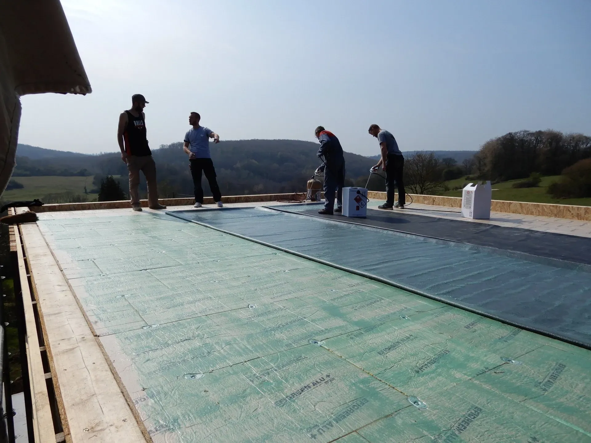 Quatre personnes en train de peindre le sol d'une maison en construction