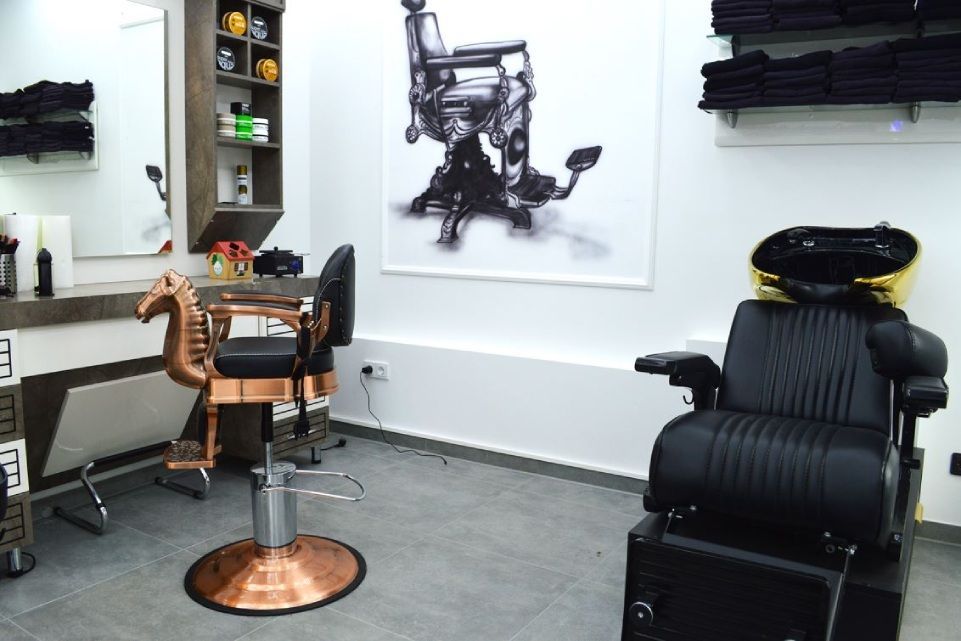 Interieur eines Friseursalons mit Ledersesseln, einem Frisierplatz aus Kupfer und schwarzer Wandkunst auf weißen Wänden