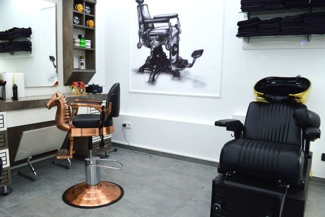 Interieur eines Friseursalons mit Ledersesseln, einem Frisierplatz aus Kupfer und schwarzer Wandkunst auf weißen Wänden