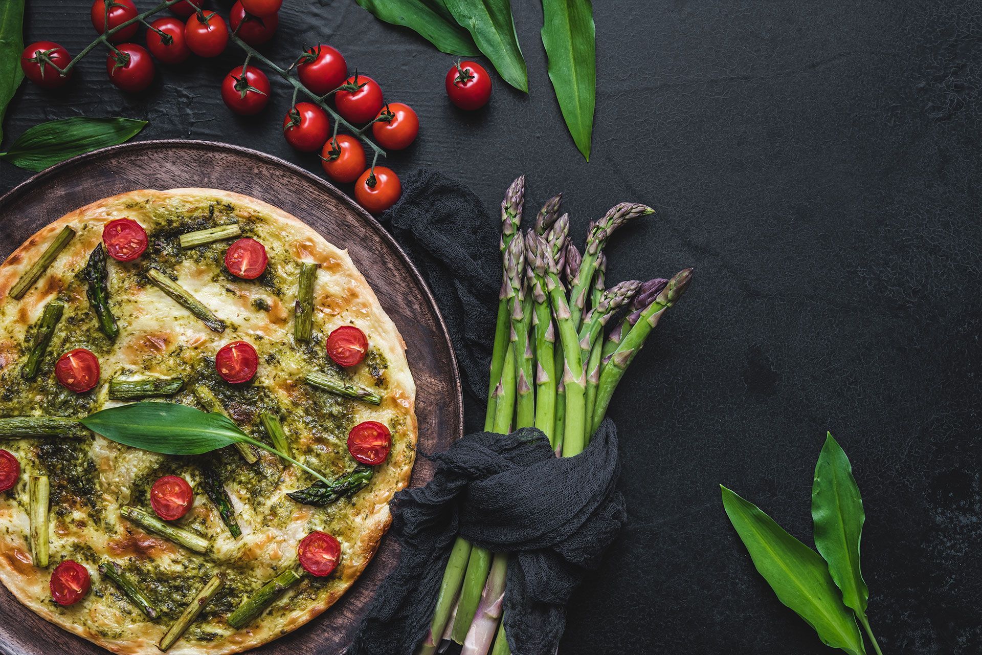 eine Pizza mit Spargel und Tomaten auf einem Teller .