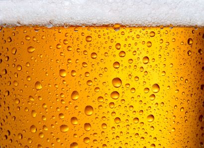 Gros plan sur un verre à bière ambrée avec des gouttelettes de condensation et une mousse à la surface.