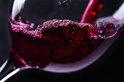 Gros plan sur du vin rouge tourbillonnant dans un verre, des gouttelettes s'écrasant contre le bord.