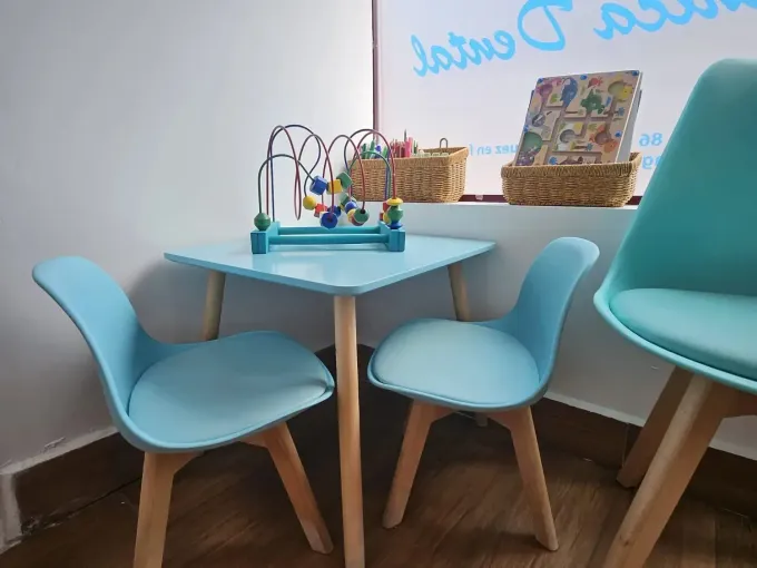 Primer plano de una persona con cabello oscuro y ondulado sonriendo, mostrando los dientes, vistiendo una blusa.