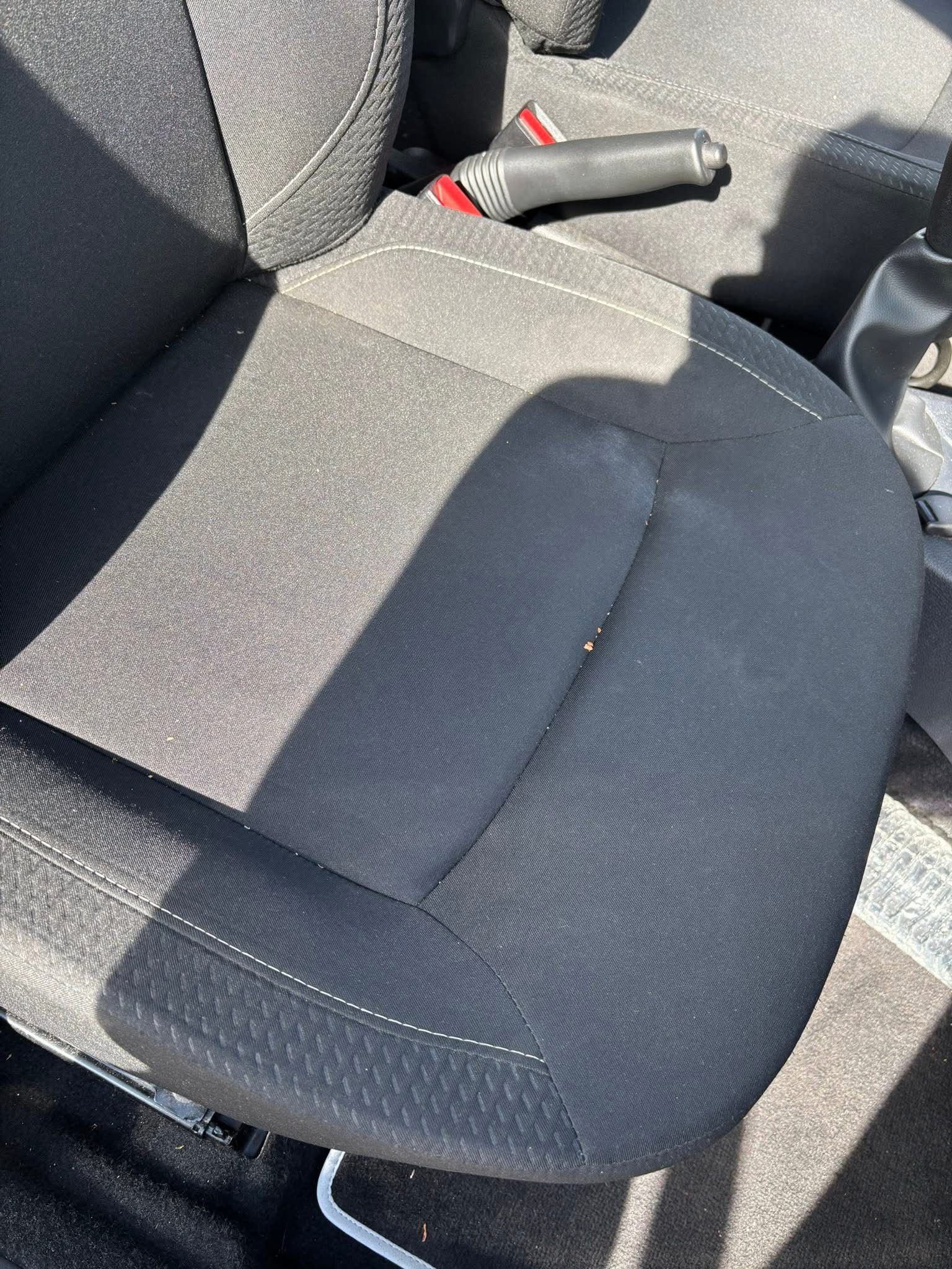 Siège auto en tissu gris foncé, coutures blanches, avec frein à main.