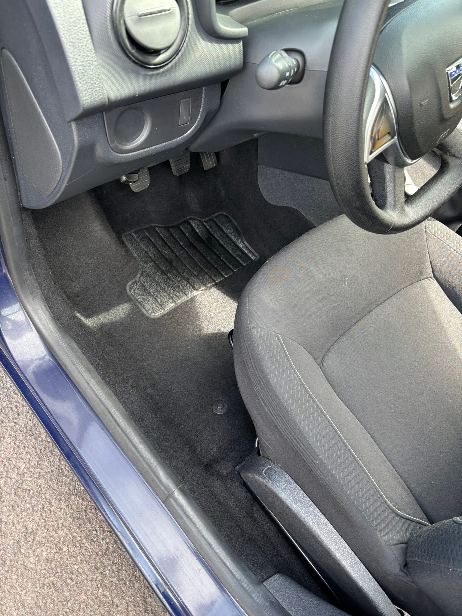 Intérieur d'une voiture avec volant, siège, pédales et tapis de sol.