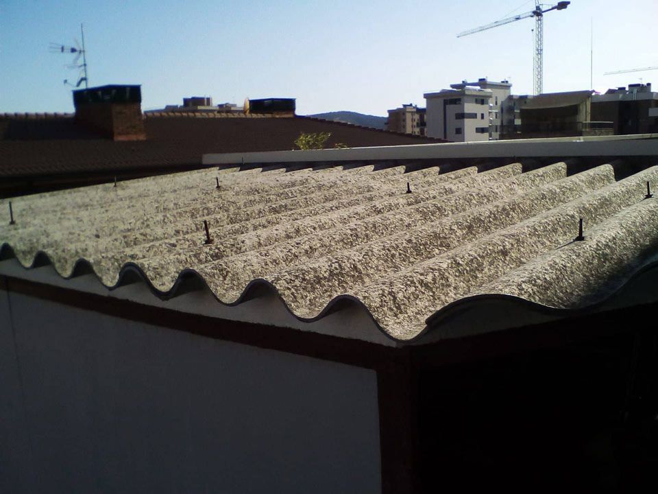 Un primer plano de un tejado con una grúa al fondo.