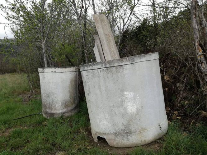 Dos grandes tubos de hormigón están tirados en el césped de un campo.