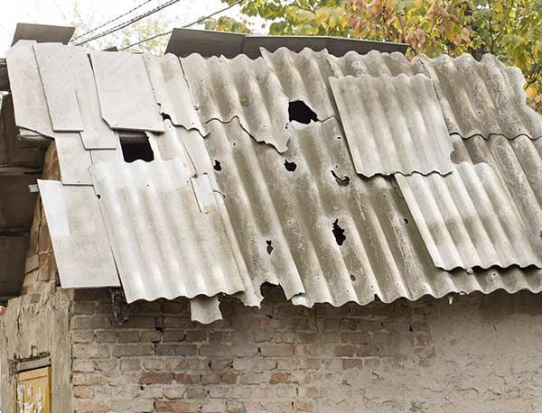 Un techo con agujeros está encima de un edificio de ladrillos.