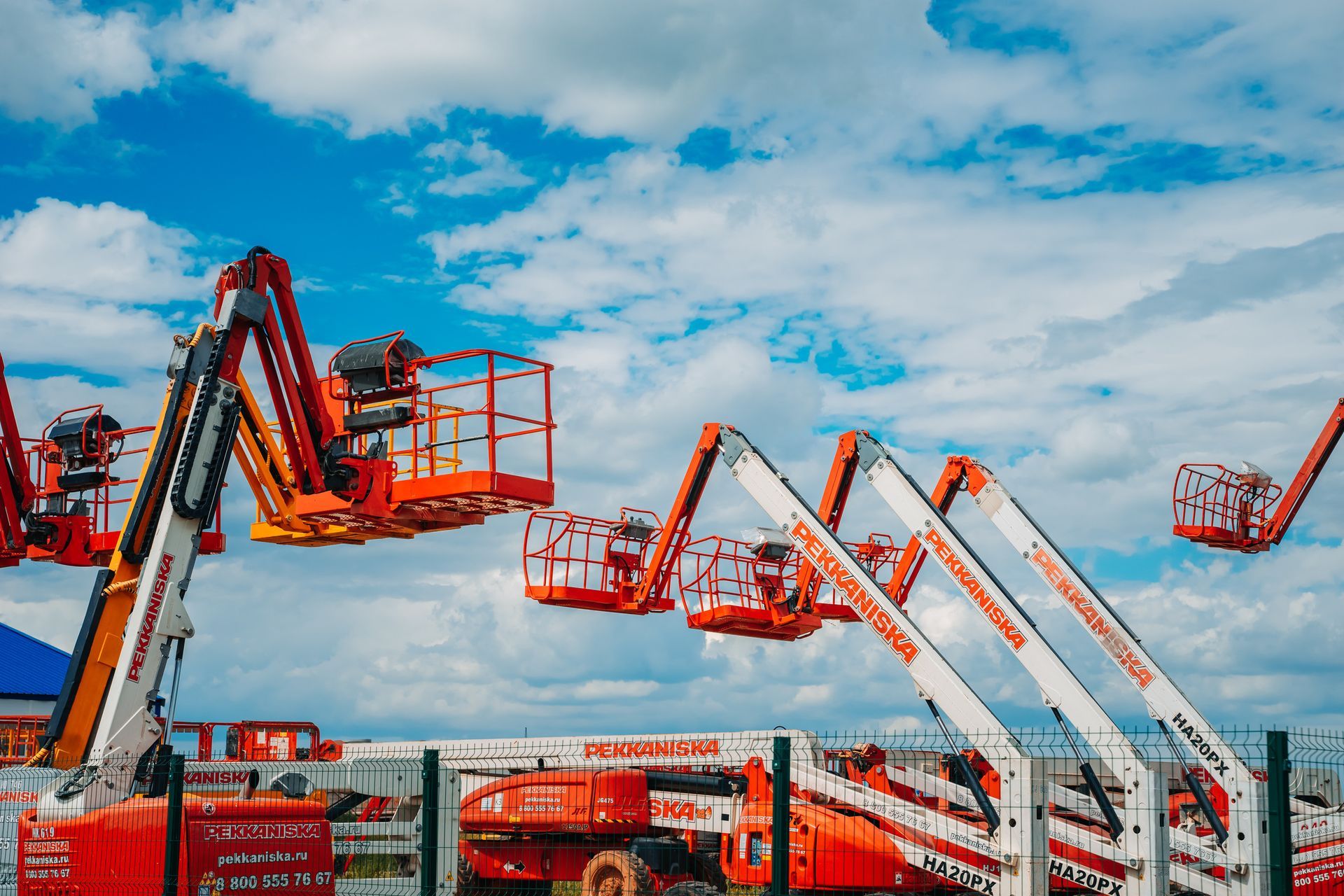 Una colección de elevadores aéreos de color naranja y blanco contra un cielo azul con nubes.