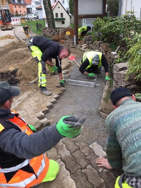 Eine Gruppe Bauarbeiter arbeitet an einem Gehweg.