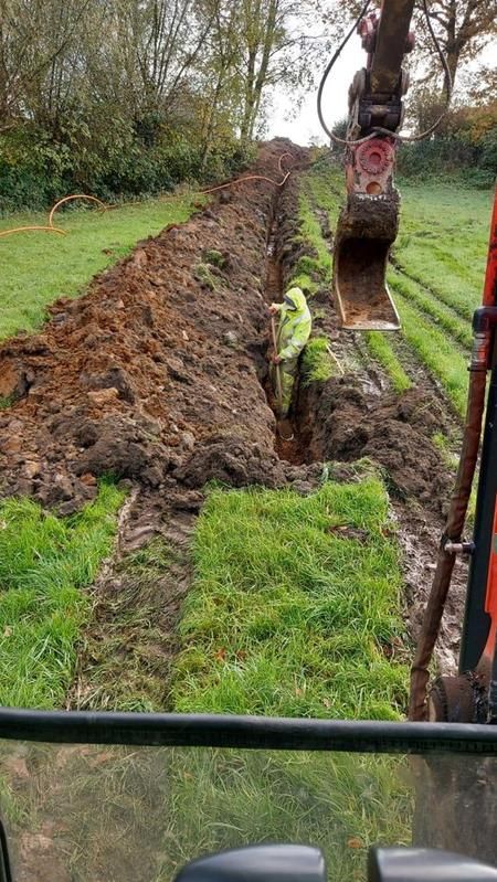 Ein Traktor gräbt auf einem Feld ein Loch in den Boden.