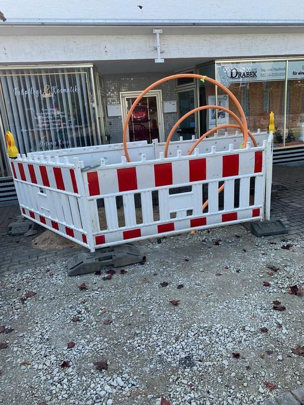 Vor einem Gebäude steht ein rot-weißer Zaun.