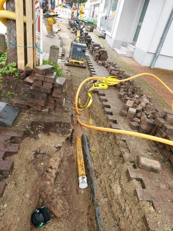 Eine Baustelle mit einem Schlauch und Ziegeln im Dreck.