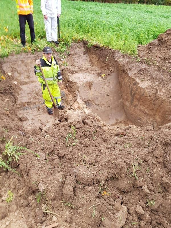 Ein Mann steht mit einer Schaufel in einem Erdhaufen.