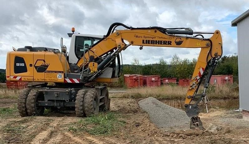 Ein gelber Bagger gräbt ein Loch in ein Erdfeld.