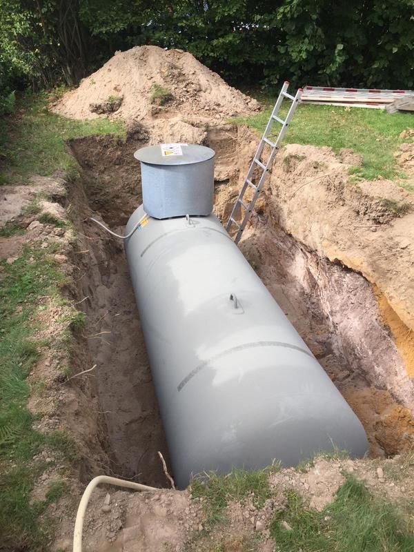Ein großer Betontank steht neben einer Leiter im Dreck.