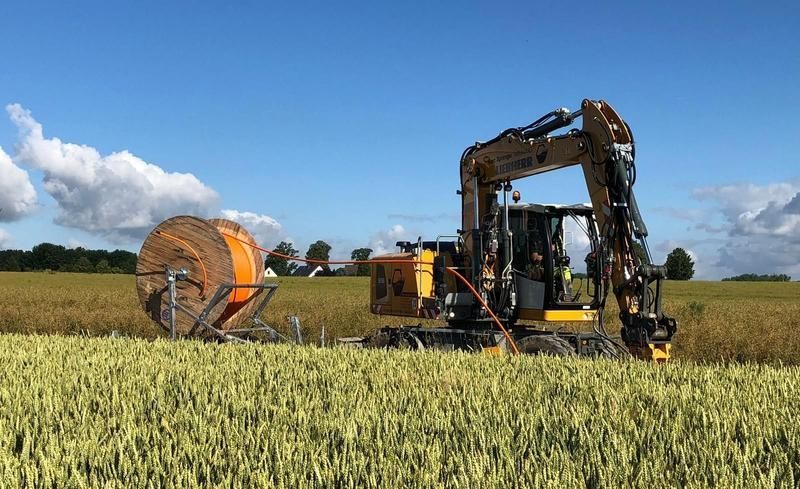 Ein gelber Bagger arbeitet in einem Weizenfeld.