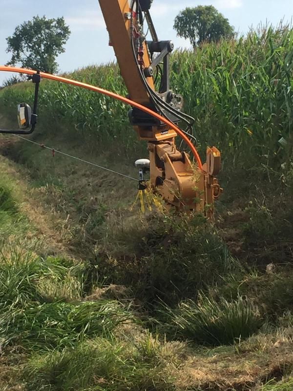 Ein Traktor mit einem daran befestigten Schlauch schneidet Gras auf einem Feld.