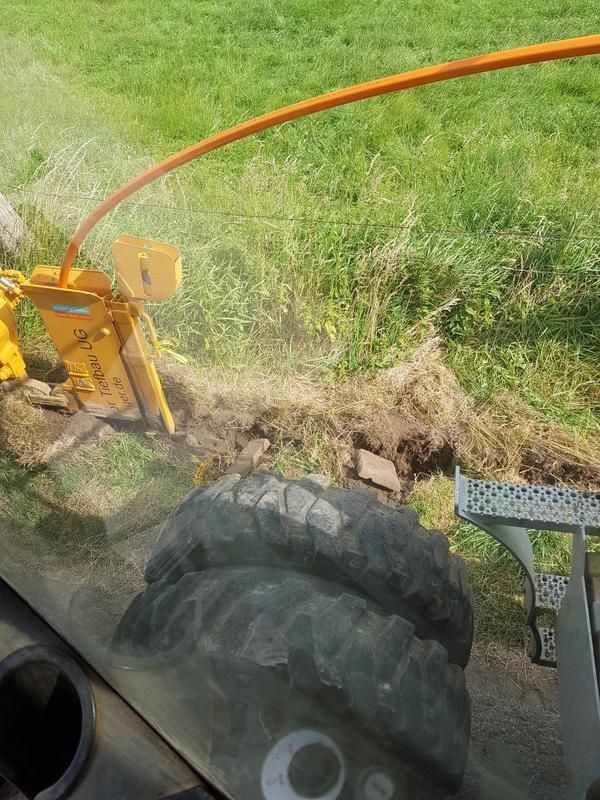 Ein Traktor schneidet auf einem Feld einen Baumstumpf ab.