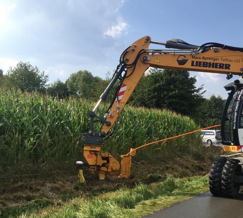 Ein gelber Liebherr-Bagger arbeitet auf einem Feld