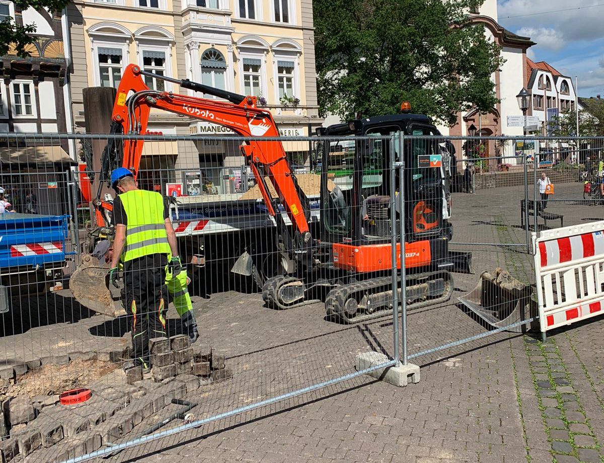 Ein Mann gräbt hinter einem Zaun ein Loch in den Boden.