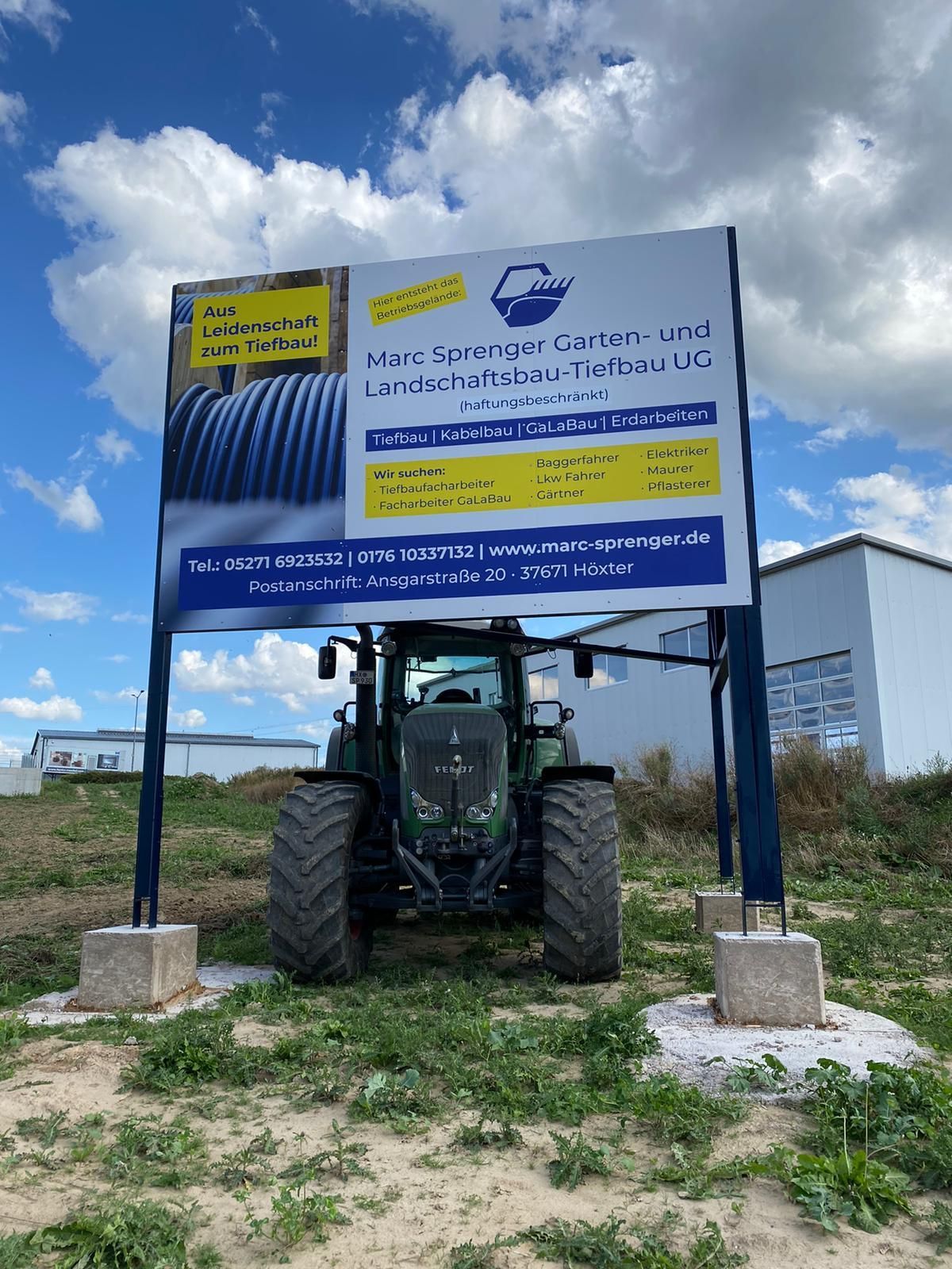 Ein Traktor steht vor einem Schild auf einem Feld.