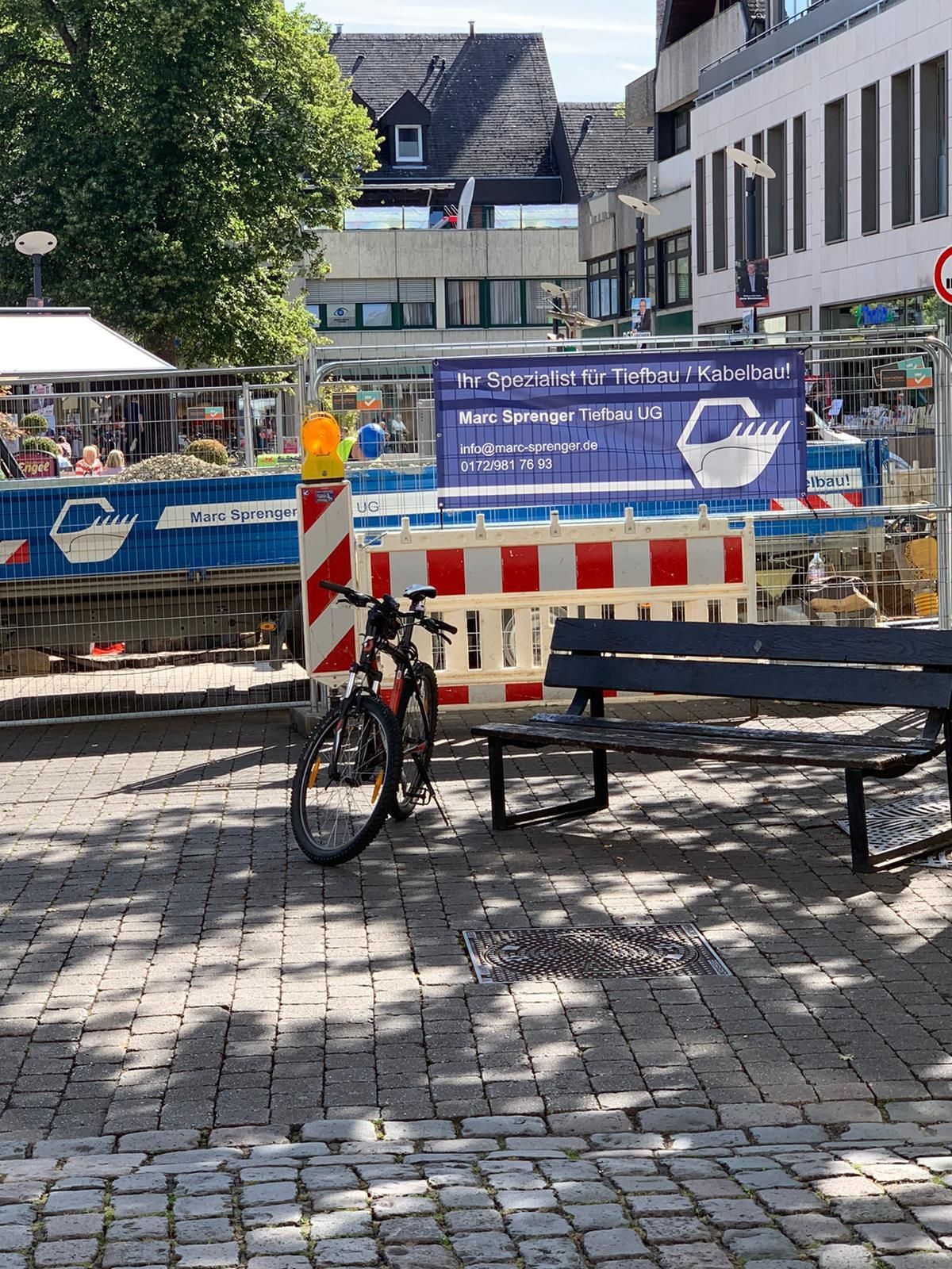 Ein Fahrrad steht auf einer Bank vor einer Baustelle.