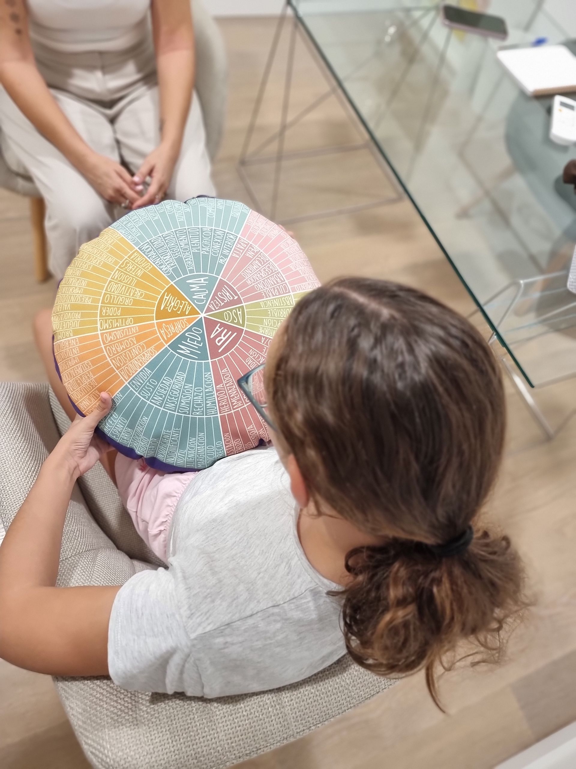 Persona sosteniendo un bolígrafo y un cuaderno, pensando, sentada en una silla.