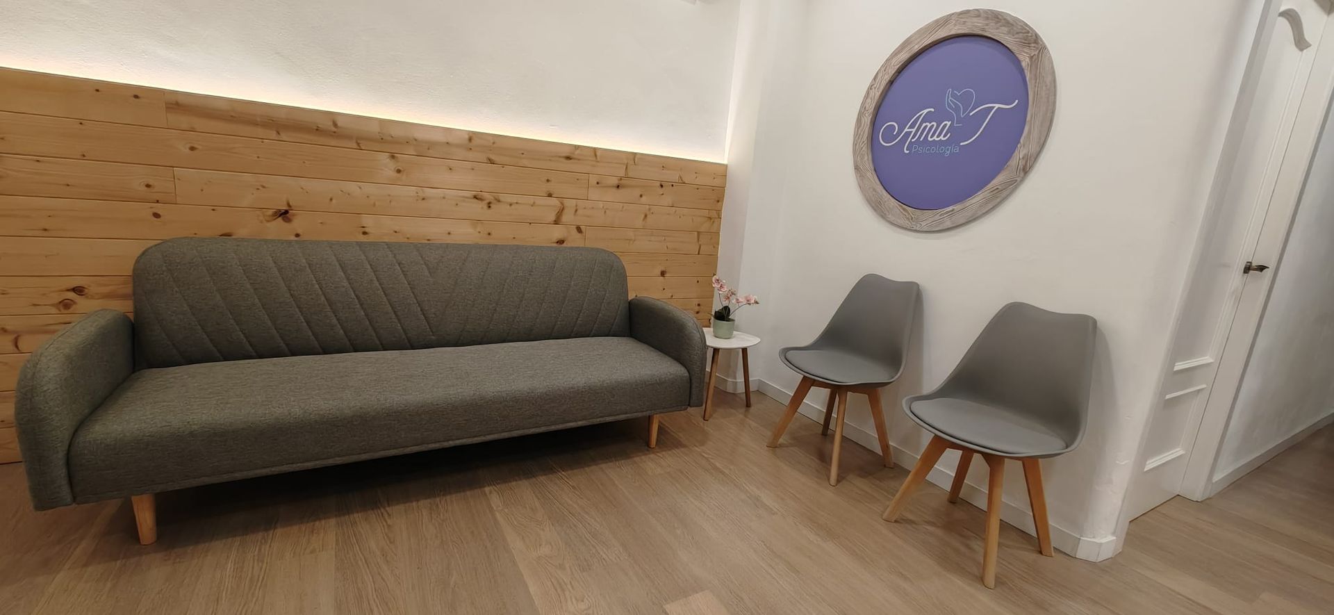 Un terapeuta hablando con una pareja en un sofá en una habitación luminosa con un jarrón de flores.