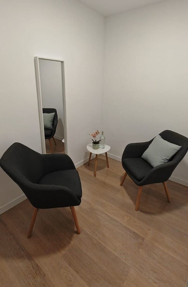 Consejero de cabello gris sosteniendo un bolígrafo, frente a dos personas en un sofá.