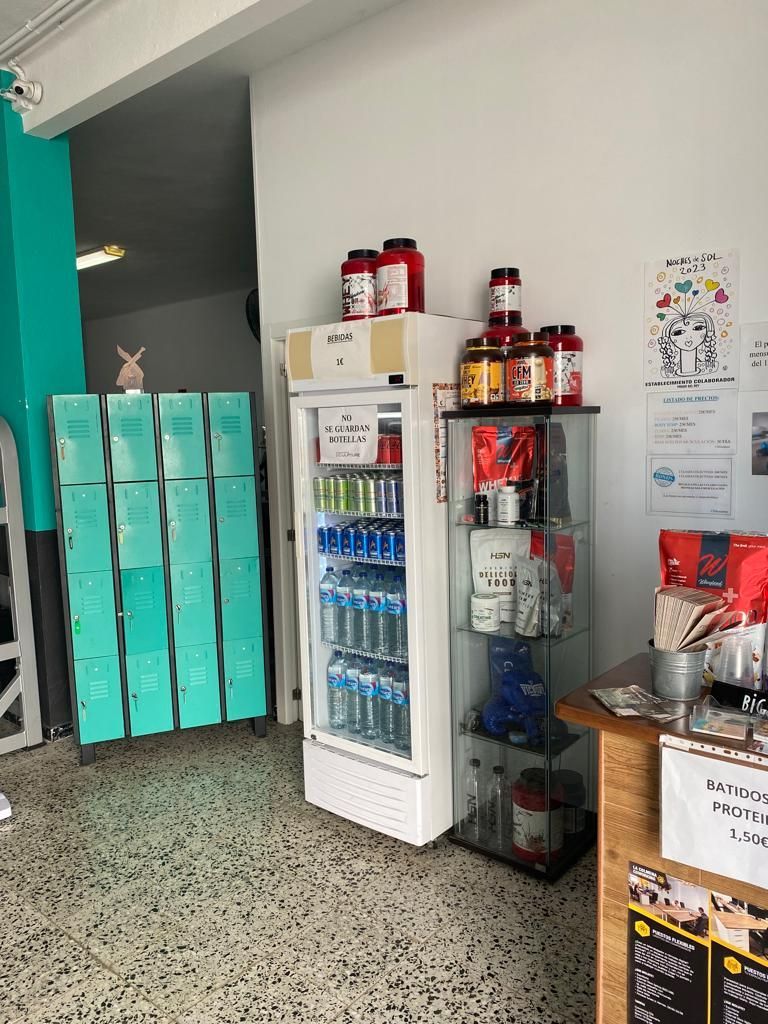 Una habitación con un refrigerador lleno de botellas de proteína en polvo.