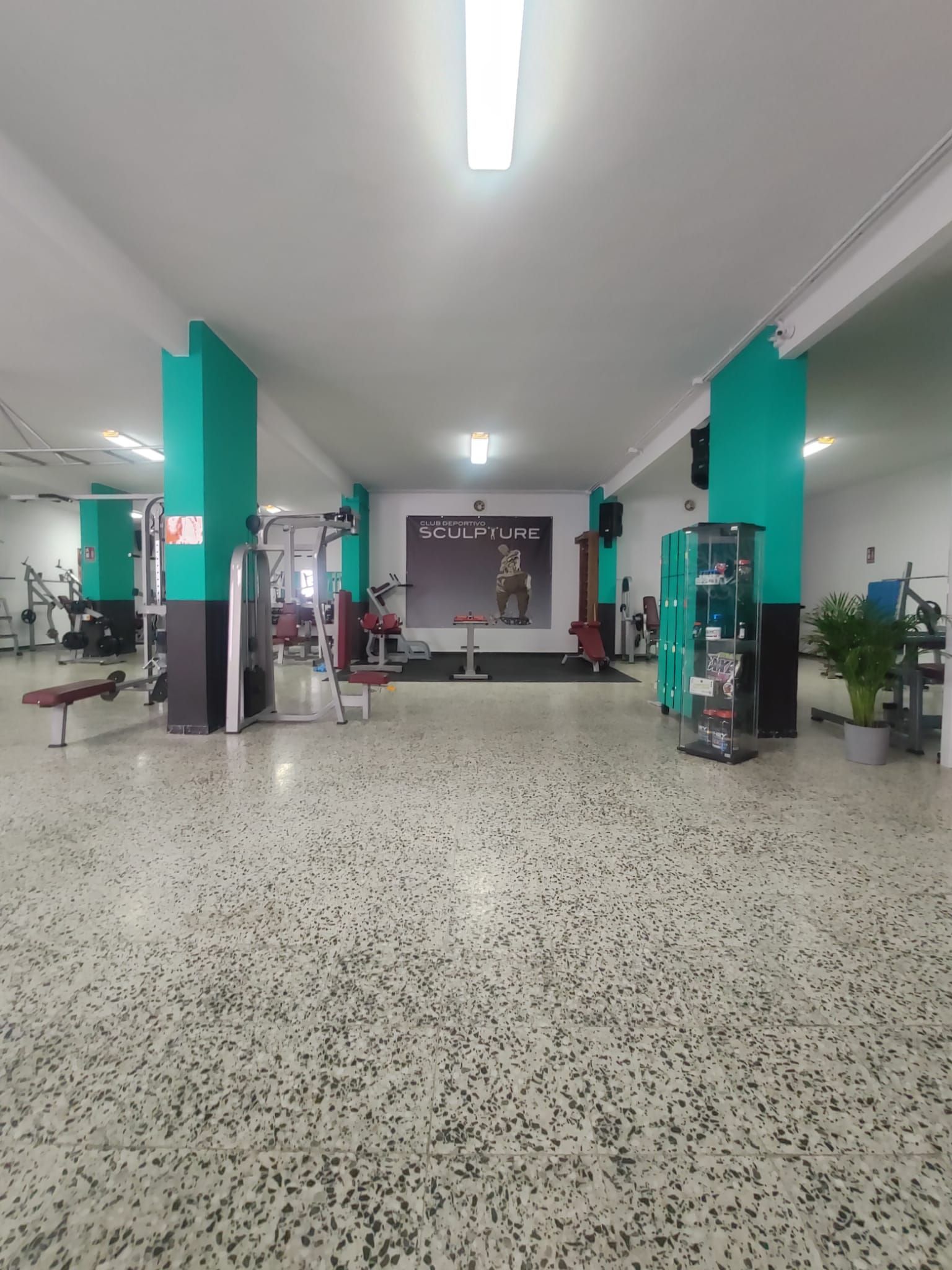 Un gimnasio con mucho equipamiento y un cuadro en la pared.