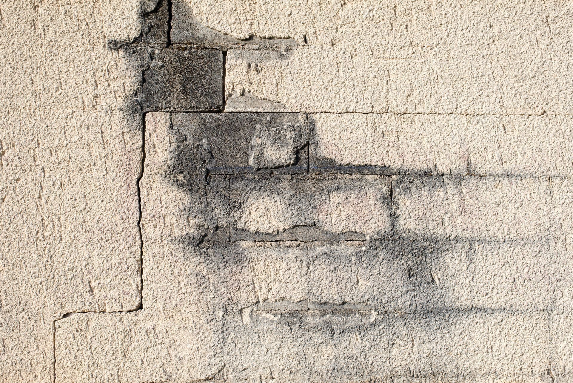 Mur en stuc fissuré, avec des briques apparentes et des traces d’humidité.