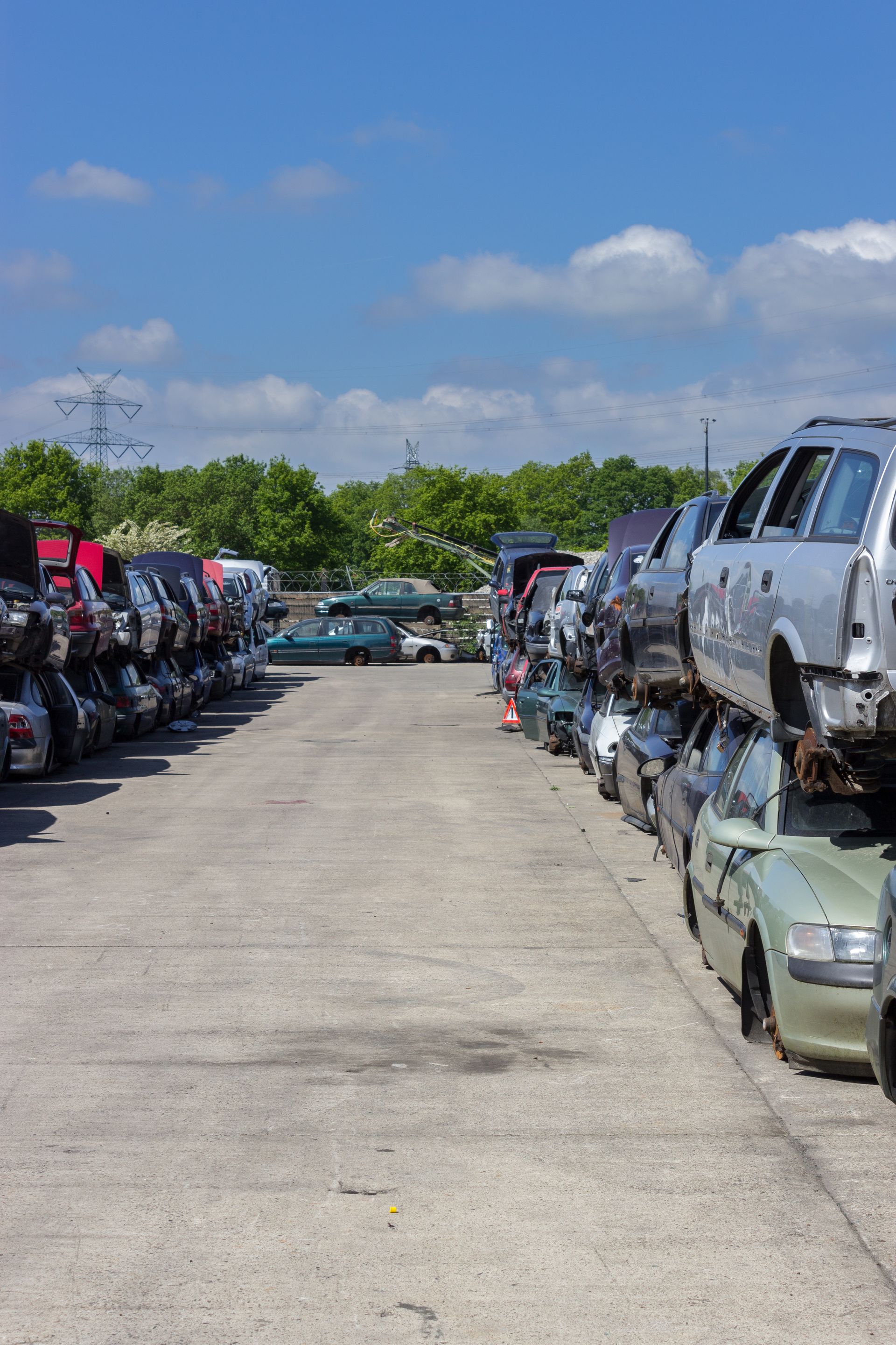 Des rangées de voitures accidentées empilées dans une casse par une journée ensoleillée.