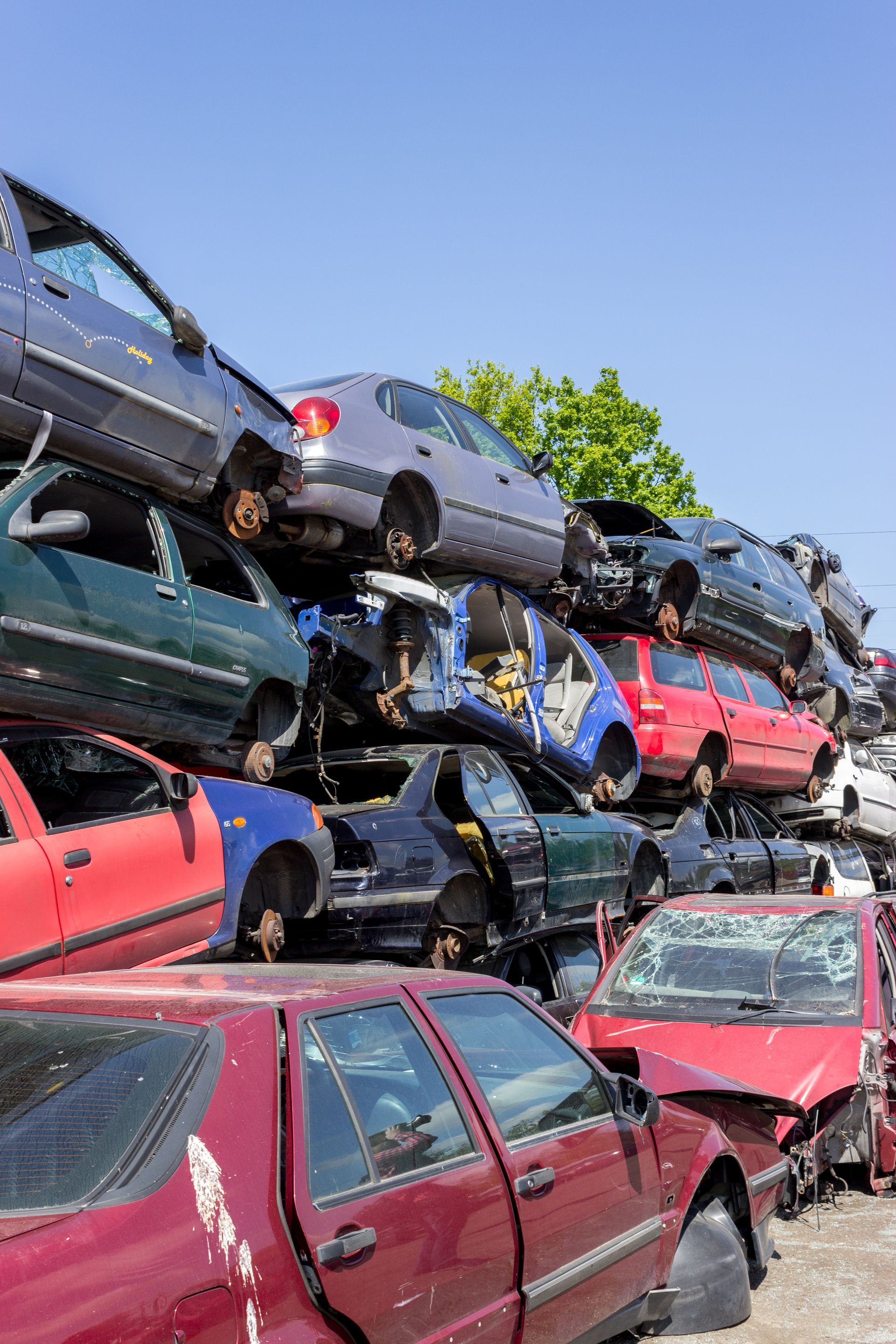 Des voitures entassées dans une casse, ciel bleu en arrière-plan.