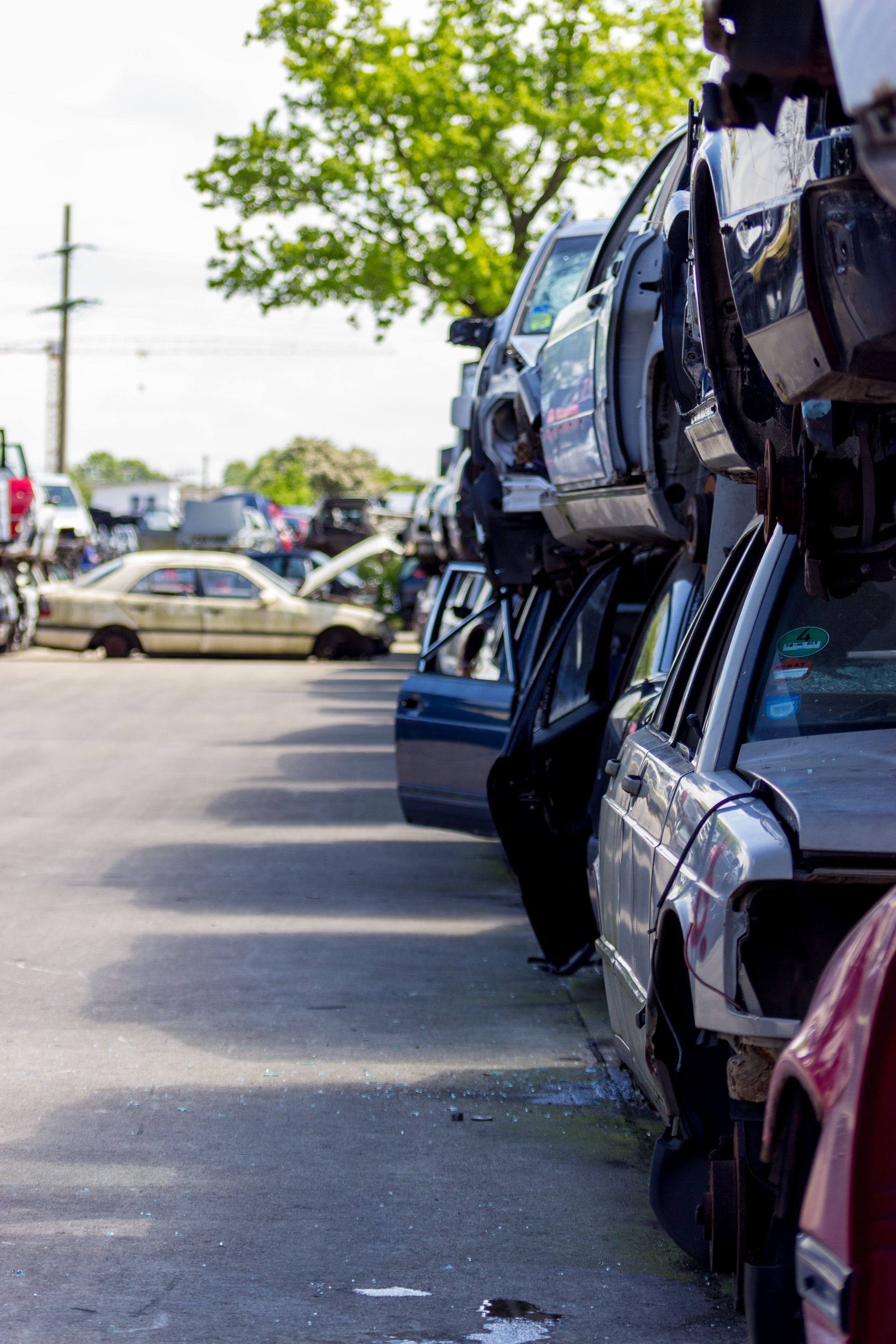 Un tas de voitures hors d'usage dans une casse. Des rangées de véhicules empilés les uns sur les autres ; bleus, gris et rouges.