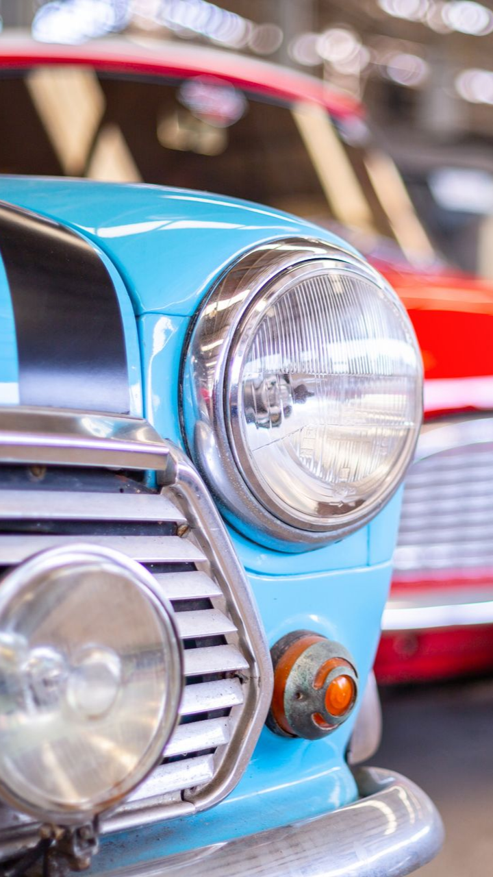 Gros plan sur une Mini Cooper classique bleu clair avec phares et calandre chromés.