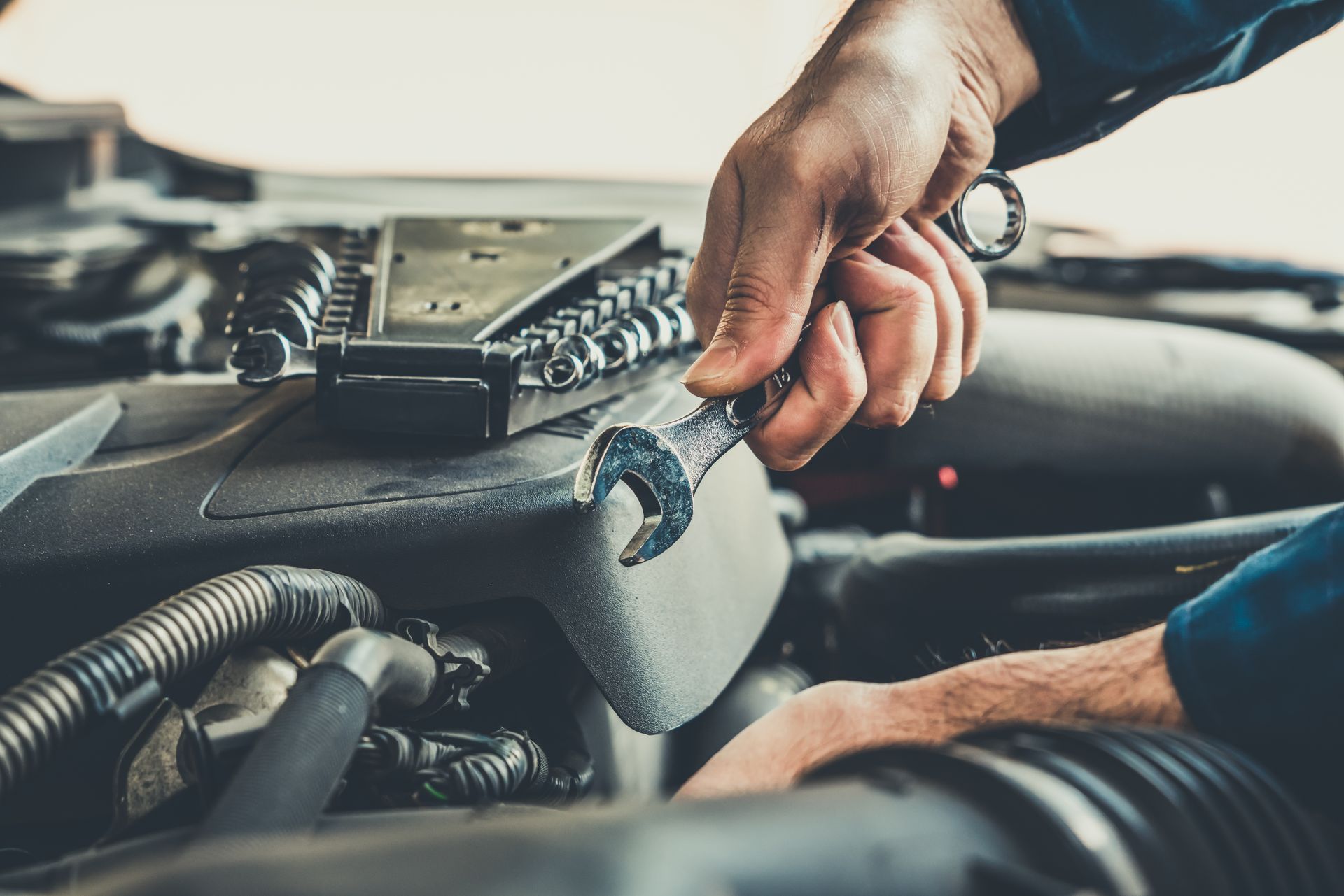 Un mécanicien utilise une clé pour réparer un moteur de voiture.