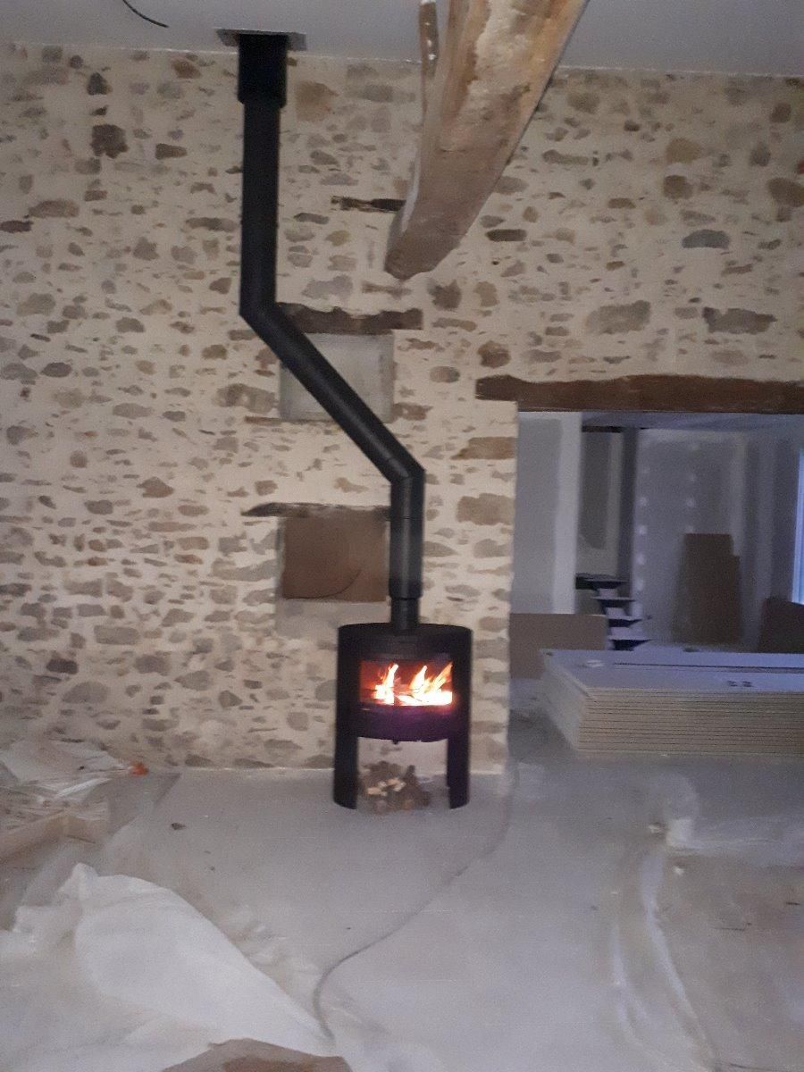 Poêle à bois installé sur un mur en pierres