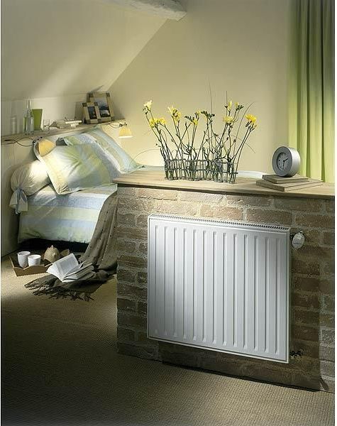 Radiateur installé sur un muret en brique dans une chambre