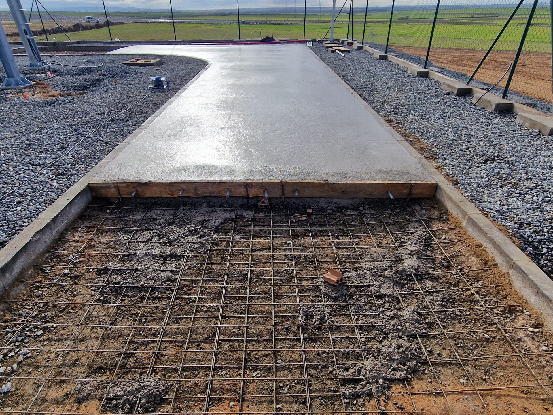 Pasarela de hormigón recién vertido con estructura de varillas de refuerzo expuestas, sitio de construcción al aire libre.