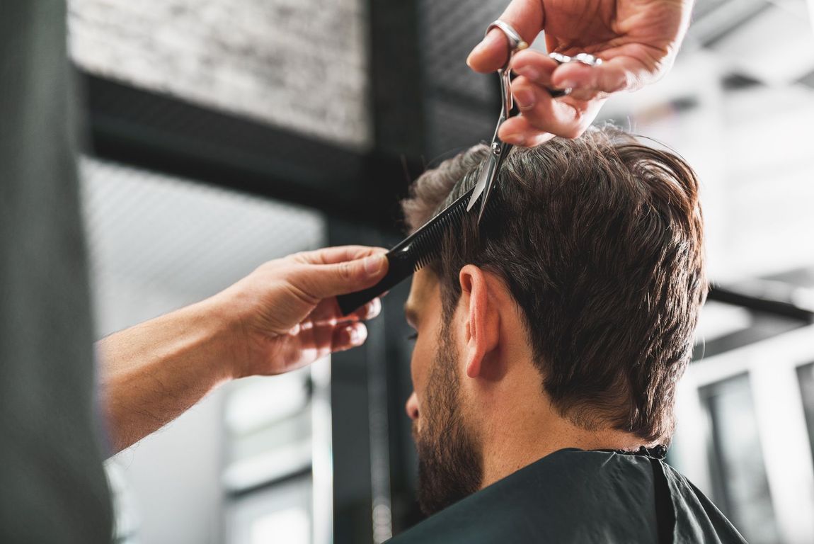 Intérieur de salon de coiffure avec postes de coiffure, miroirs et étagères présentant des produits.