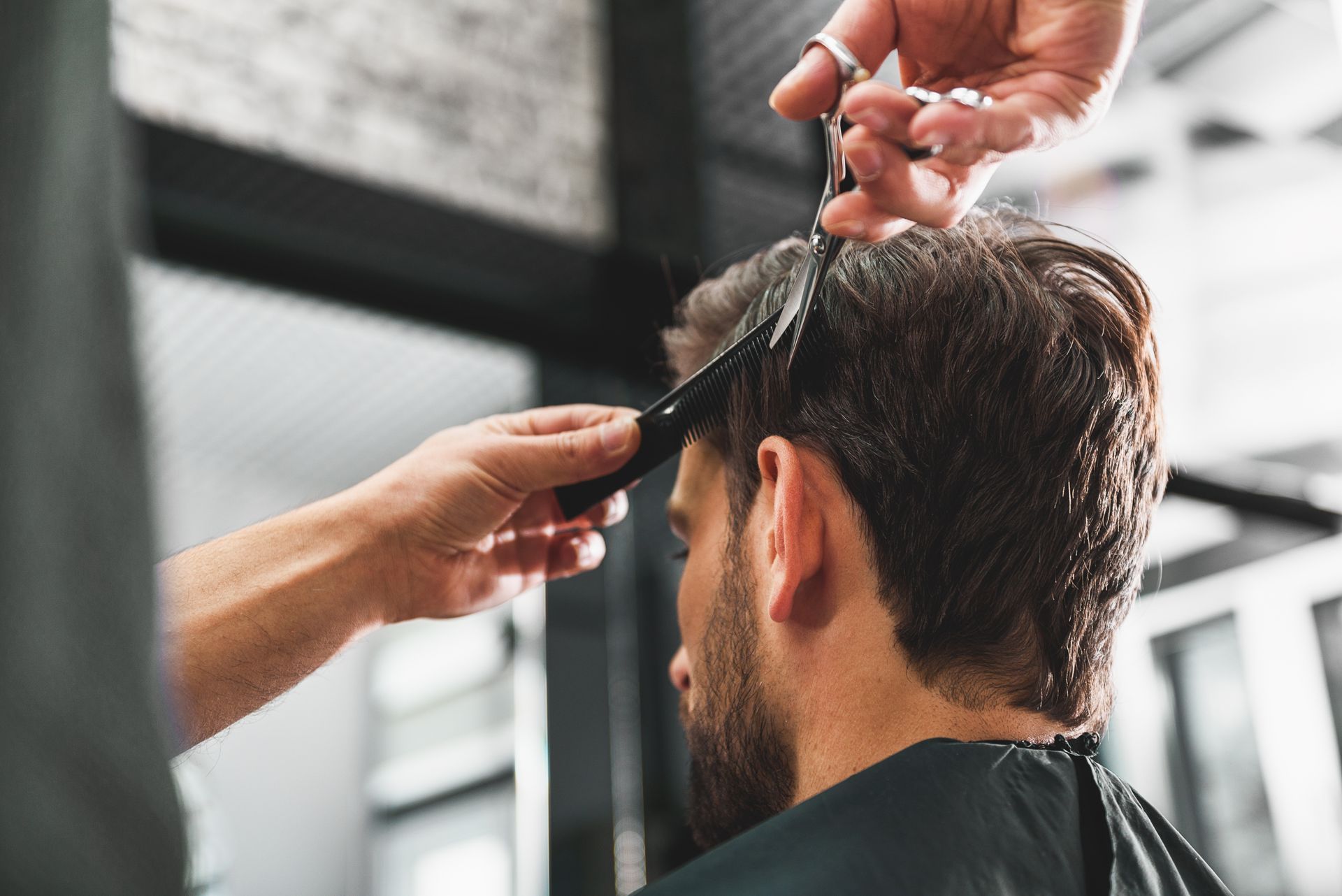 Intérieur de salon de coiffure avec postes de coiffure, miroirs et étagères présentant des produits.
