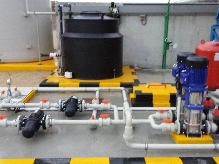 Equipo industrial en una plataforma amarilla con rayas negras; incluye un gran tanque negro.