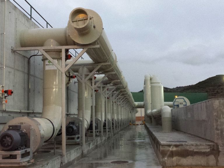 Vista exterior del sistema de ventilación industrial con tuberías y ventiladores de color beige