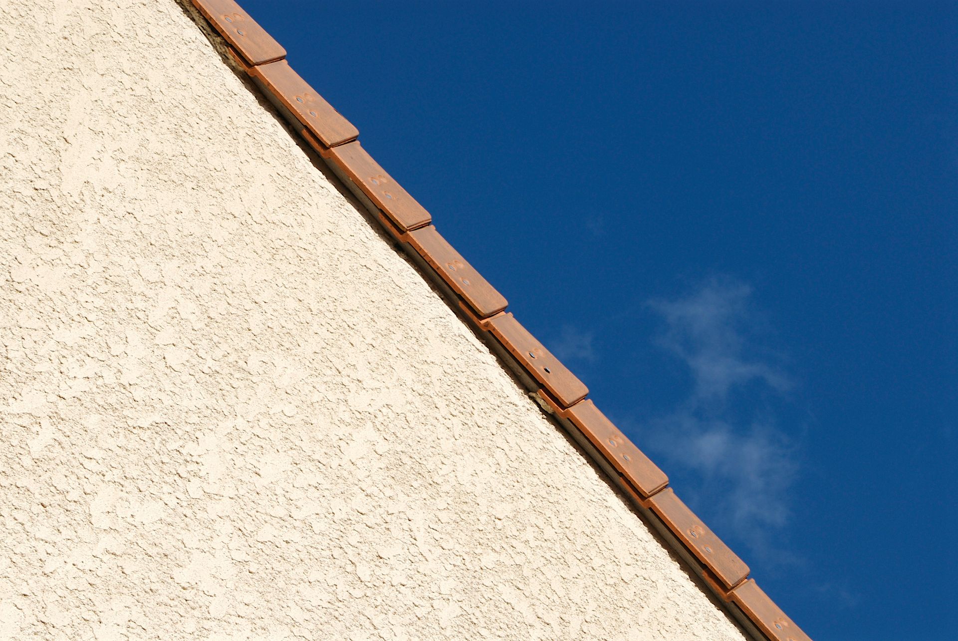 Façade en crépi beige et jonction avec la toiture