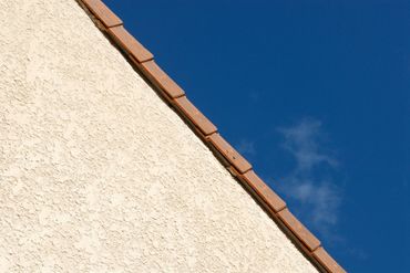 Façade en crépi beige et jonction avec la toiture